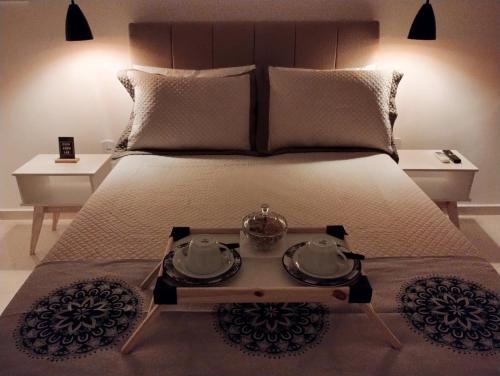 a bed with a table with two dishes on it at Suítes Casa Verde in Saquarema