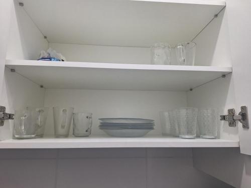 a white shelf with glasses and dishes on it at ap with suite prox Aeroporto in São José dos Pinhais