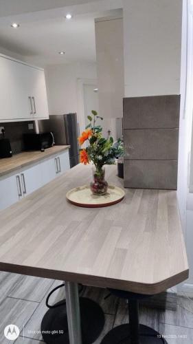 a table with a vase of flowers on it in a kitchen at Affordable 3 bed house Stoke-on-Trent for families and contractors in Stoke on Trent