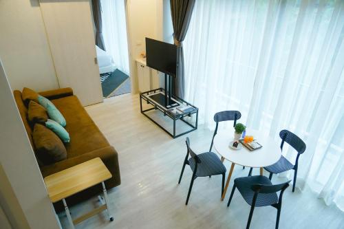 a living room with a couch and a table with chairs at TREX Buriram Boutique Hotel in Buriram