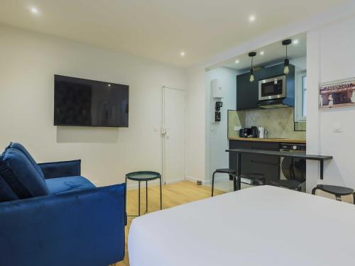 un salon avec un canapé bleu et une cuisine dans l'établissement Modern studio - 4P- Sacré-Coeur, à Paris