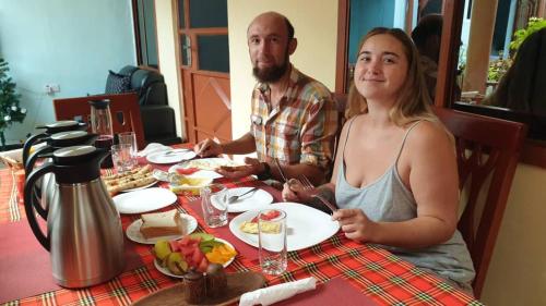 a man and woman sitting at a table eating food at Kisanga Homestay in Moshi