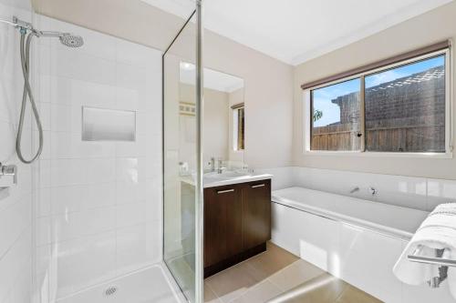 y baño blanco con ducha, bañera y lavamanos. en Hartleigh Estate - Sophisticated Family Living, en Clyde