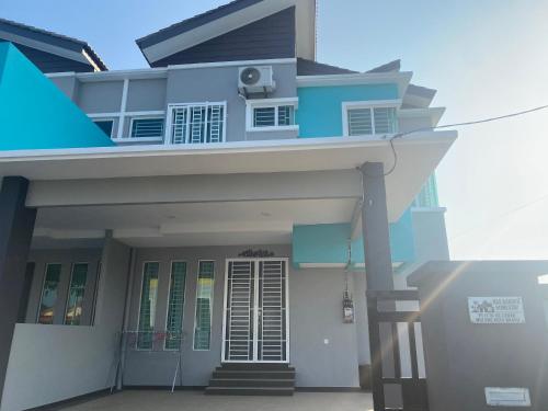 una casa blu e bianca con portico di Ras Garden Homestay a Kampong Larak