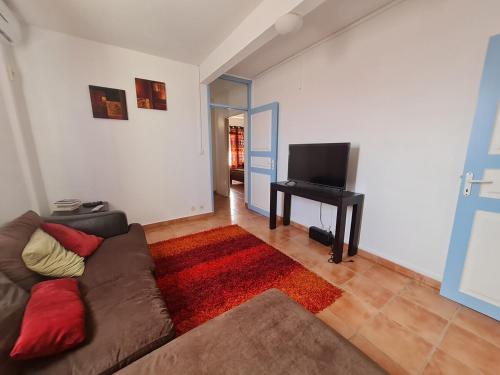 Una sala de estar con un sofá y un televisor de pantalla plana. en La Brise du Levant, en Capesterre