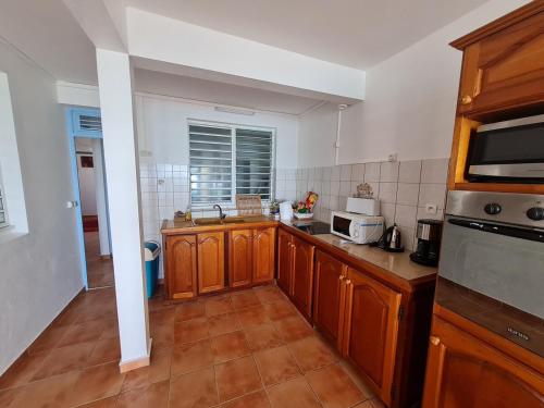 Una cocina con gabinetes de madera y encimera. en La Brise du Levant, en Capesterre