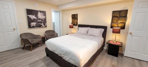 a bedroom with a bed and two chairs in it at Holiday Hideout Basement Unit in Pickering