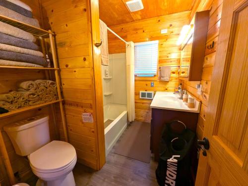 a bathroom with a toilet and a sink and a tub at Yellowstone Treasure Guesthouses on the River in Gardiner