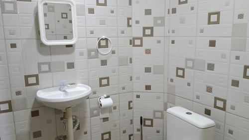 a white bathroom with a sink and a toilet at Casa a Beira Mar em Itamaracá in Itamaracá