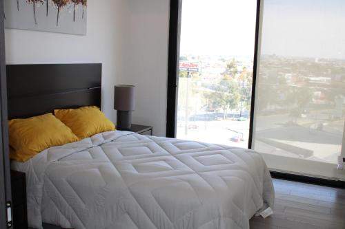 a bedroom with a white bed with a large window at Loft Cerca Plaza Mayor in Miravalle