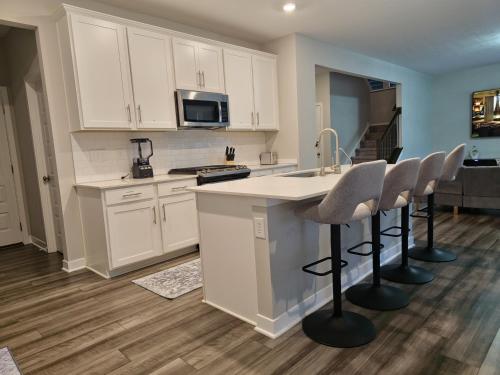 a kitchen with white cabinets and a kitchen island with bar stools at Cozy 5 bedroom and 4 bathroom in Brownsburg