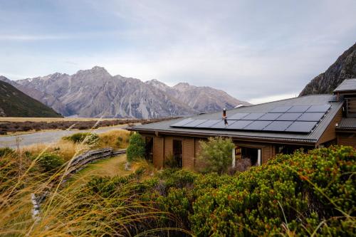a house with solar panels on the roof with mountains in the background at Haka House Aoraki Mt Cook in Mount Cook Village