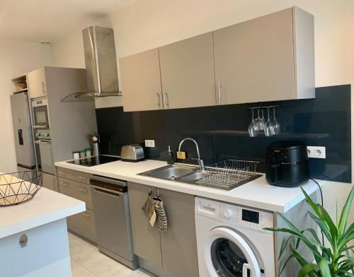 une cuisine avec un évier et une machine à laver dans l'établissement Spacious and central apartment, à Reims