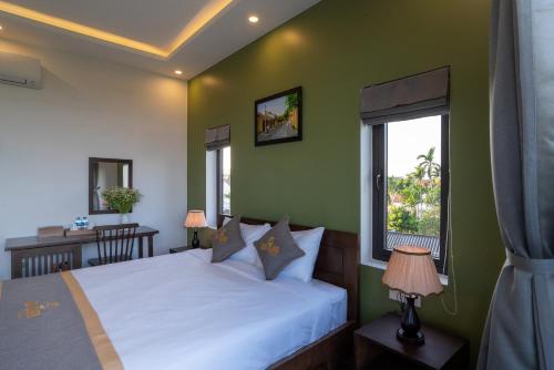 a bedroom with a bed and a desk and a window at Coco Island Villa in Hoi An