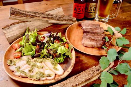 a table with two plates of food and a salad at Minamiaso BlueBeeGarden in Minami Aso