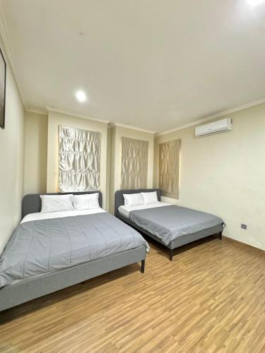 two beds in a room with wooden floors at De Lavender Villa 1 in Citaringgul 1