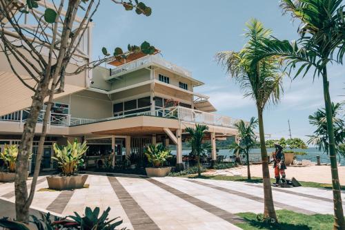 a building on the beach with palm trees in front at Amaka Ocean Living Lodge in Golfito