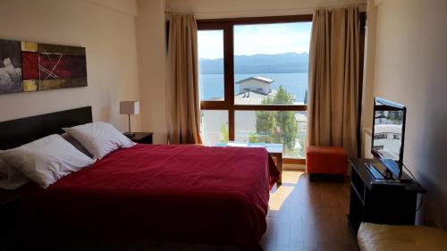 a bedroom with a red bed and a large window at Terrazas Bariloche in San Carlos de Bariloche
