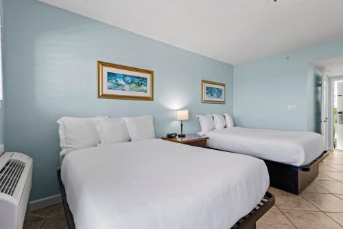 two beds in a room with blue walls at Oceanfront Inn Room #18- Ocean View Balcony 2 Full Beds in Fort Pierce