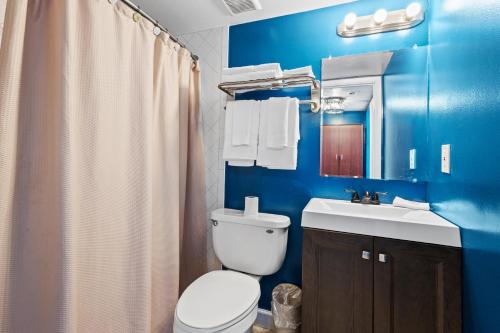 a blue bathroom with a toilet and a sink at Oceanfront Inn Room #20- Ocean View Balcony 2 Full Beds in Fort Pierce