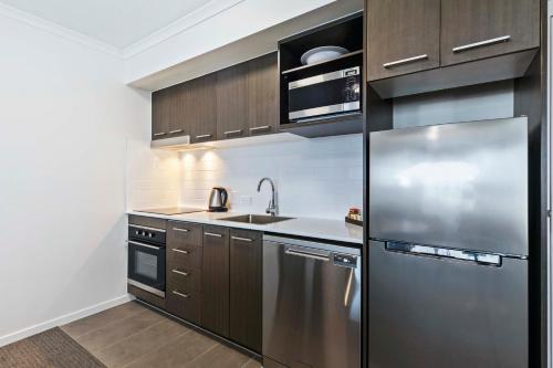 a kitchen with a stainless steel refrigerator and a sink at Quest Chermside in Brisbane
