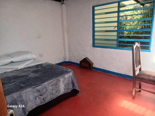 a bedroom with a bed and a chair and a window at Hospedaje Del Toro in San Augustín