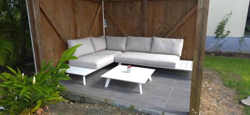 a white couch and a table on a patio at Maison Laurencia - Appartement au rez-de-chaussée avec jardin in Sainte-Anne