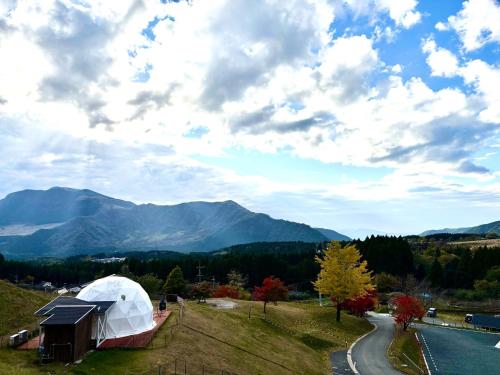 a white dome tent on a field with mountains in the background at Minamiaso BlueBeeGarden in Minami Aso