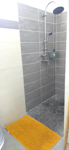 a bathroom with a shower with a yellow rug at Maison Laurencia - Appartement au rez-de-chaussée avec jardin in Sainte-Anne