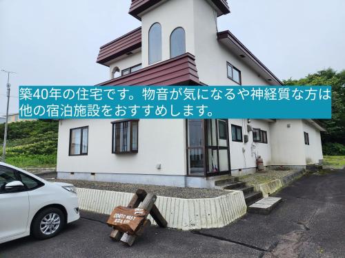 OdaitōGuest House ODAITO NEST的一辆白色汽车停在一栋建筑物前
