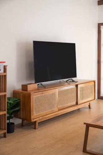 a flat screen tv sitting on top of a wooden entertainment center at Thongkwao house in Chiang Mai