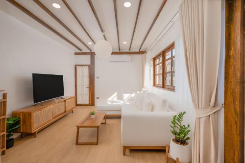 a living room with a white couch and a tv at Thongkwao house in Chiang Mai