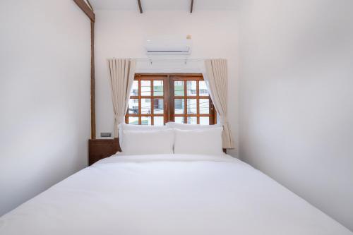 a bed with white pillows in a room with a window at Thongkwao house in Chiang Mai