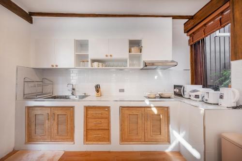 a kitchen with white walls and wooden cabinets at Thongkwao house in Chiang Mai