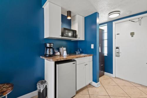 a kitchen with blue walls and white cabinets at Oceanfront Inn Room #17- Ocean View Balcony King Bed in Fort Pierce