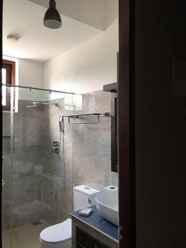 a bathroom with a shower and a toilet and a sink at Sadasee Villa in Bandaragama