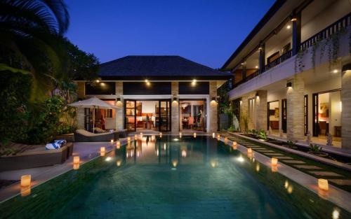 a swimming pool in front of a house at night at The Residence Seminyak in Seminyak