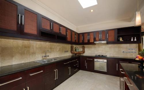 a large kitchen with wooden cabinets and a sink at The Residence Seminyak in Seminyak