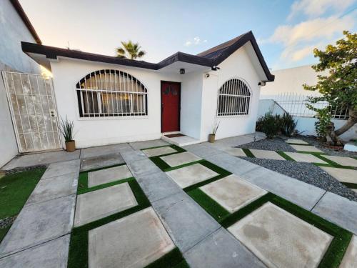 a white house with a red door and grass at Casita Patz Ensenada in Ensenada