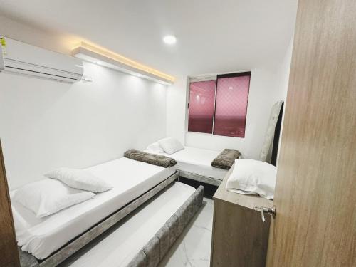 two beds in a small room with a window at Apto nuevo al lado de la UNorte, 10 Min Buena vista Grav vista in Barranquilla