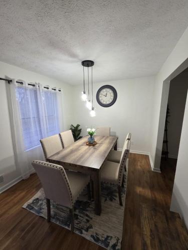 a dining room table with chairs and a clock on the wall at Charming 3 bedrooms in the heart of Alpharetta in Alpharetta