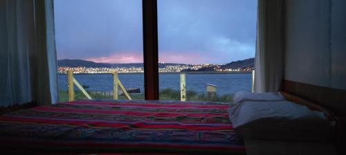 a bedroom with a large window with a view of the water at Titicaca Halso Lodge in Puno