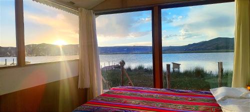 a bedroom with a view of a lake from a window at Titicaca Halso Lodge in Puno