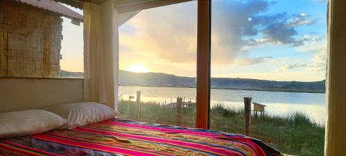 a bedroom with a large window with a view of the water at Titicaca Halso Lodge in Puno