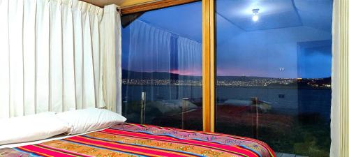 a bedroom with a large window with a view at Titicaca Halso Lodge in Puno