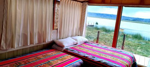 a bed in a room with a large window at Titicaca Halso Lodge in Puno