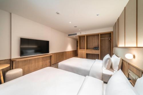 a hotel room with two beds and a flat screen tv at Sotetsu Grand Fresa Bangkok in Bangkok