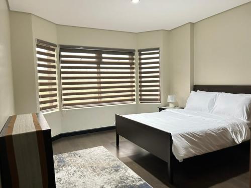 a bedroom with a bed and a large window at Crosswinds Nature View Suite in Tagaytay