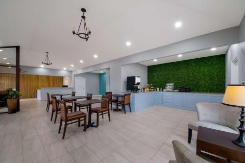 a waiting room with tables and chairs and a green wall at Rodeway Inn & Suites Corpus Christi Northwest in Corpus Christi