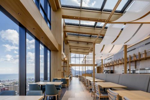 a dining room with tables and chairs and windows at Beppu SUGINOI HOTEL in Beppu